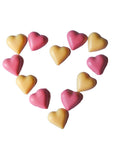 Heart-shaped slowcocoa chocolate pieces in pink and yellow on a white background