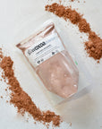 Package of Slowcocoa cacao powder with cacao powder around its perimeter