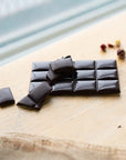 Dark chocolate bar with pieces on a wooden surface