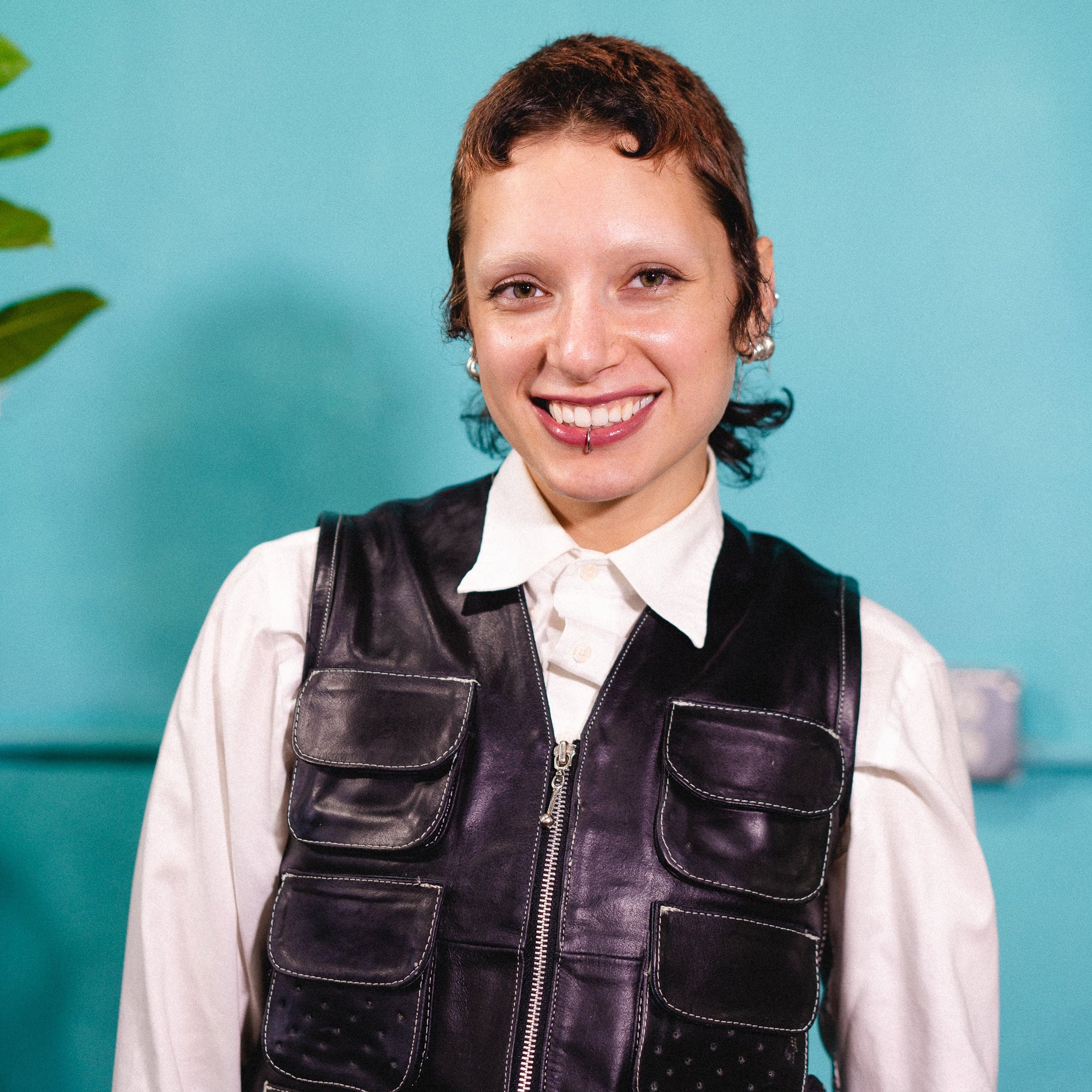Person wearing a black vest over a white shirt against a teal background