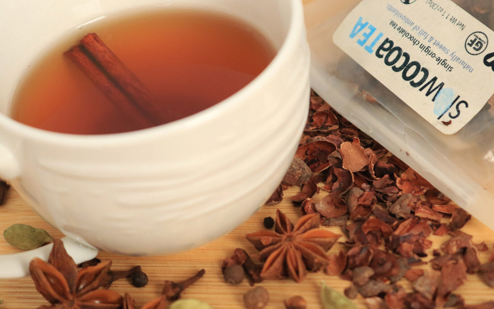 slowcocoa spiced cacao tea in a white cup with a cinnamon stick, star anise, cloves and cardamom, made from single-origin cacao husks