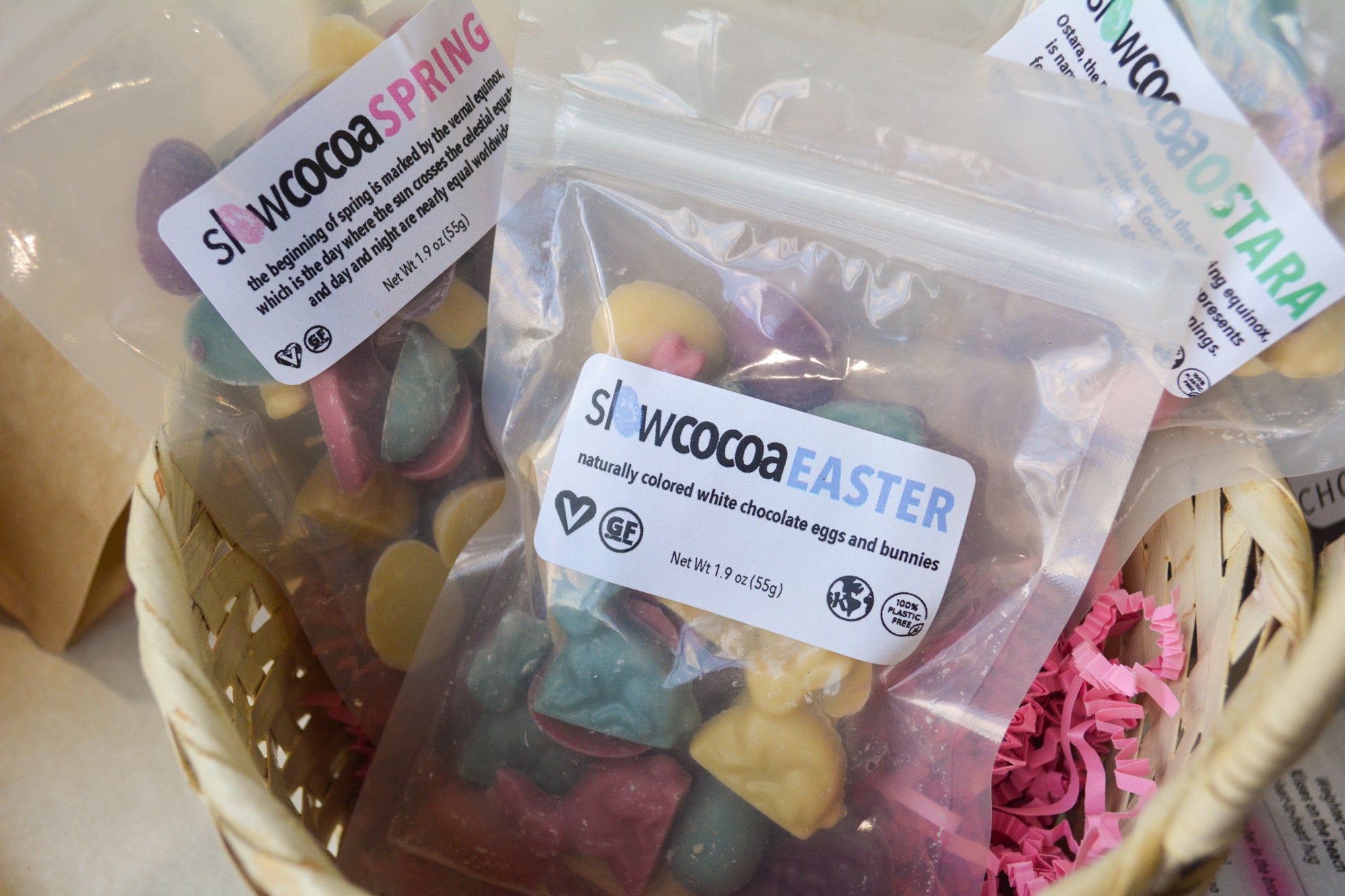 Basket with bags of colorful Easter-themed white chocolate eggs and bunnies labeled slowcocoa Easter, Spring or Ostara.