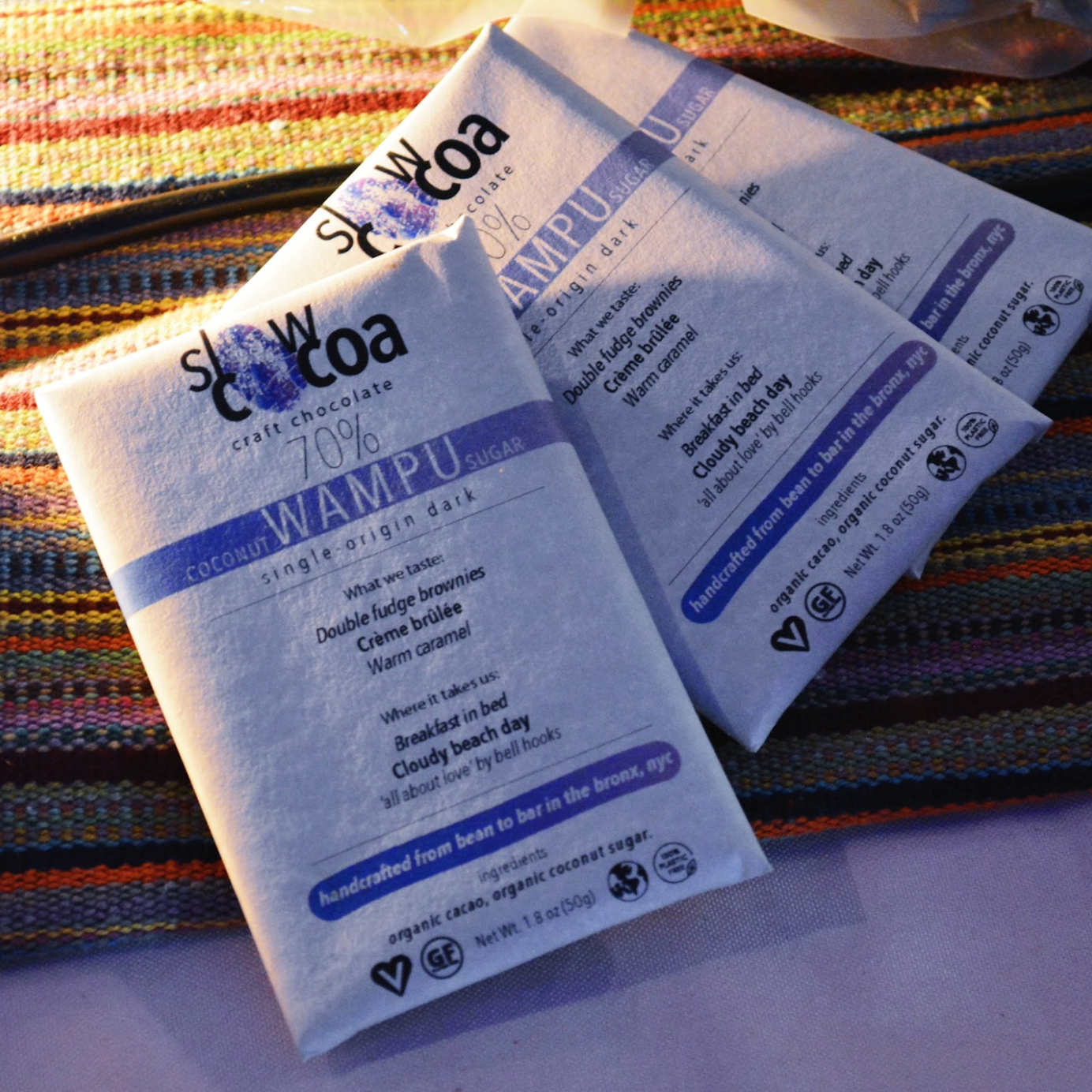 Two packages of slowcocoa 70% Wampu chocolate on a striped fabric background