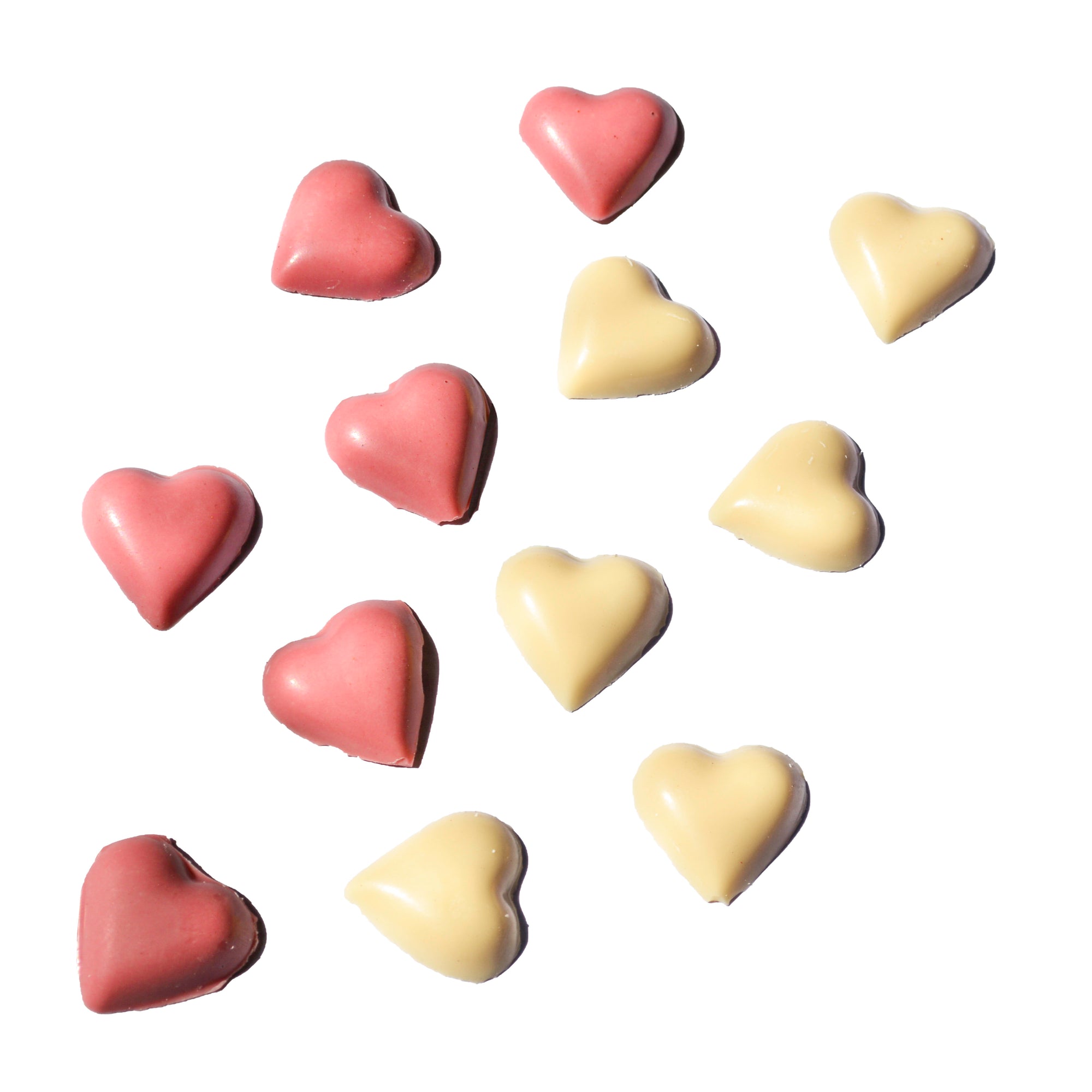 Heart-shaped slowcocoa chocolates in pink and yellow on a white background