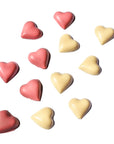 Heart-shaped slowcocoa chocolates in pink and yellow on a white background