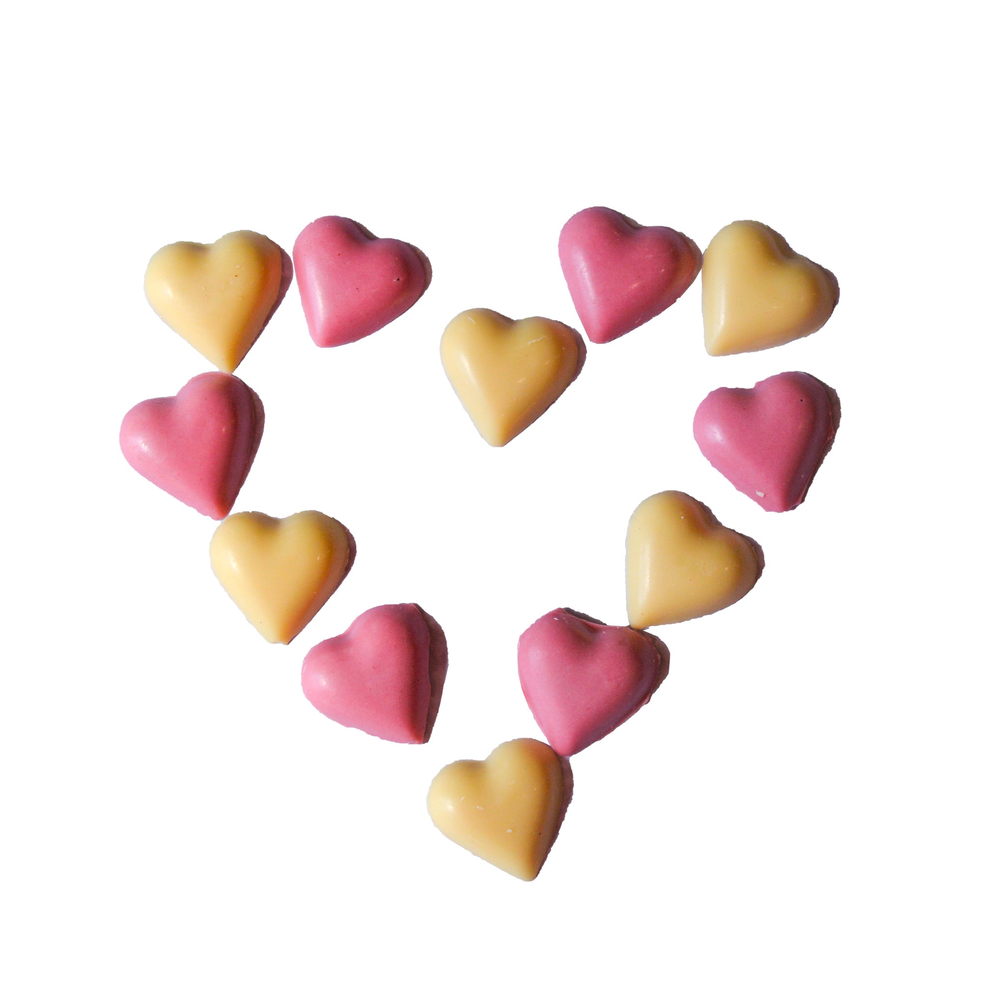 Heart-shaped slowcocoa chocolate pieces in pink and yellow on a white background