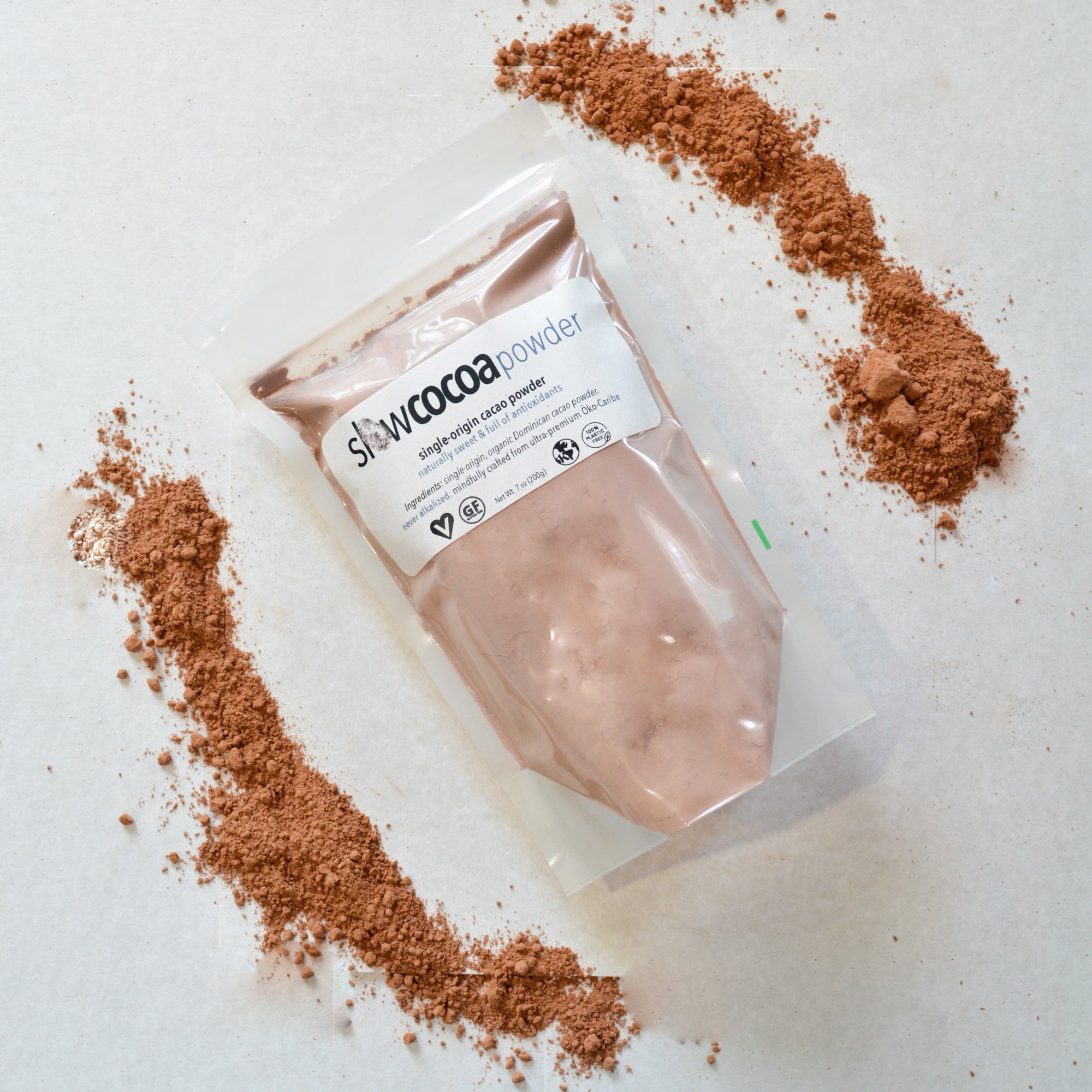 Package of Slowcocoa cacao powder with cacao powder around its perimeter