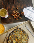 slowcocoa 100% Puerto Rico single-origin dark chocolate wrapper on a platter beside fresh-pitted dates, nut paste and a no-bake dessert served with fork and knife