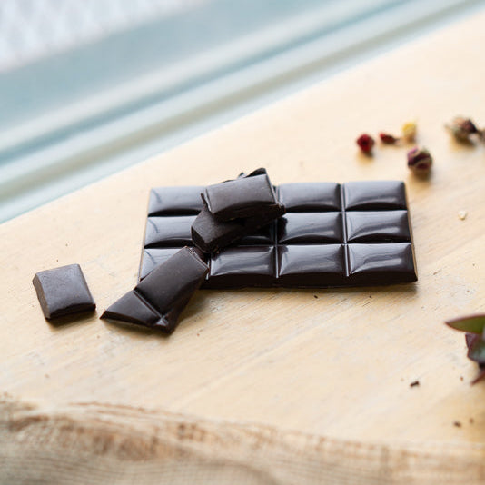 Dark chocolate bar with pieces on a wooden surface