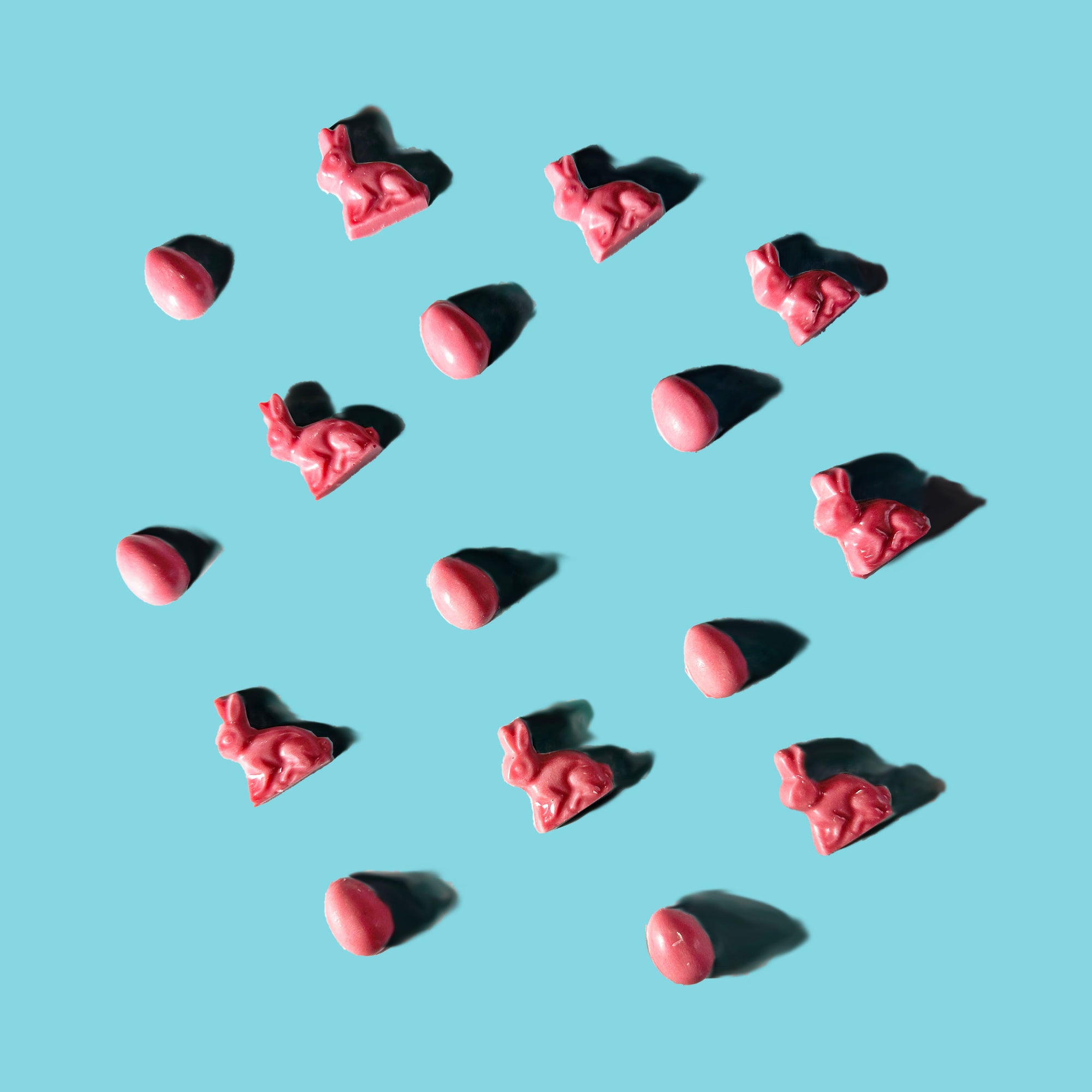 Red heart-shaped slowcocoa chocolate bunnies and Easter eggs on a light blue background